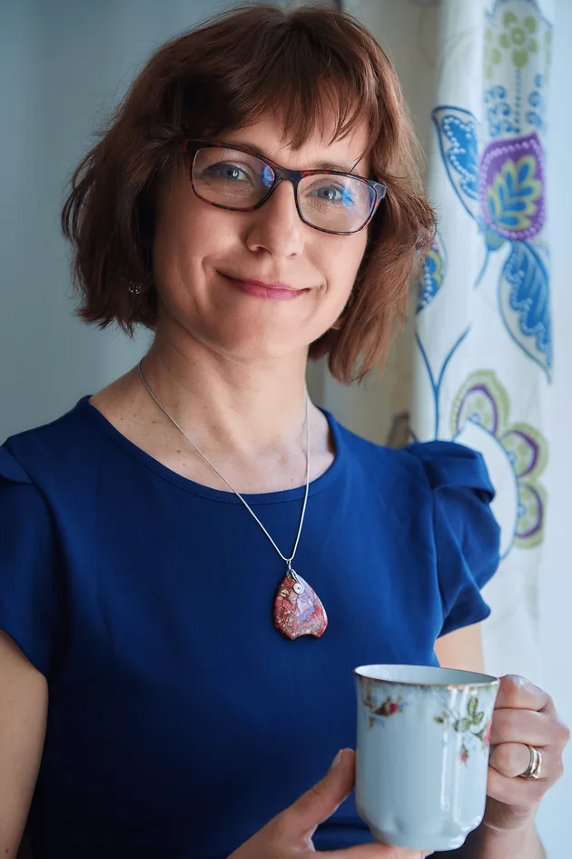 Ela Pękalska, founder of Zest Acupuncture & Chinese Medicine, smiling and holding a cup of tea.