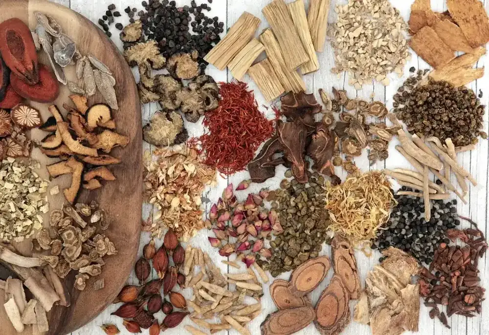A selection of dried Chinese medicinal herbs and roots arranged on a wooden board.