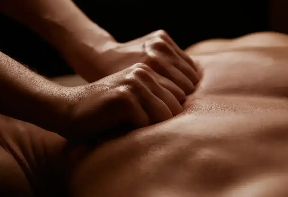A practitioner's hands pressing slowly and deeply into the muscles of a client's back.