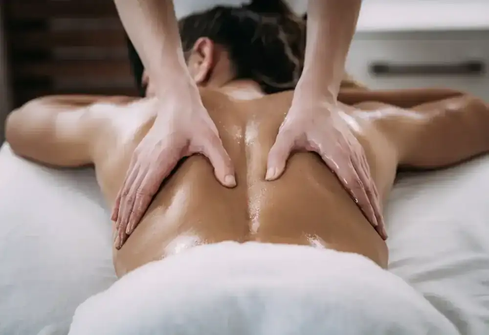 Hands press firmly into a person's back during a bodywork treatment.