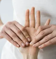 Two hands gently pressing into an open palm during treatment.