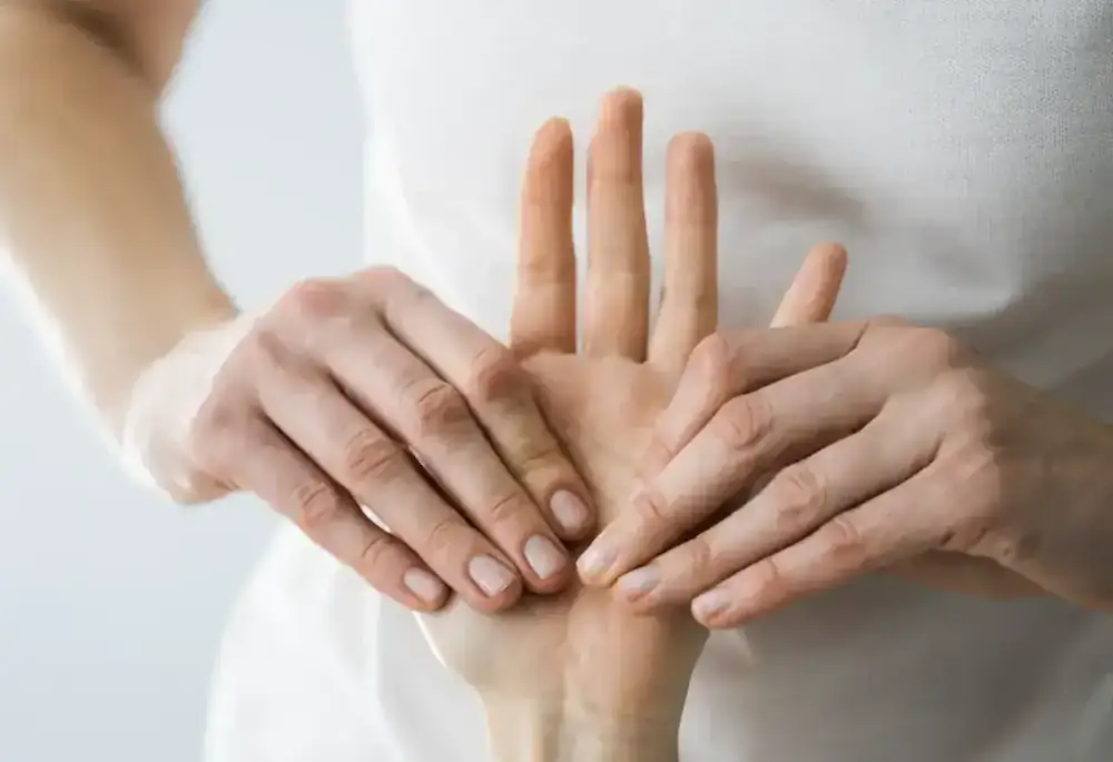 Two hands gently pressing into an open palm during treatment.