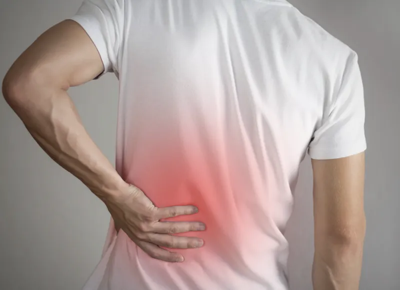 A man holds his lower back in pain.