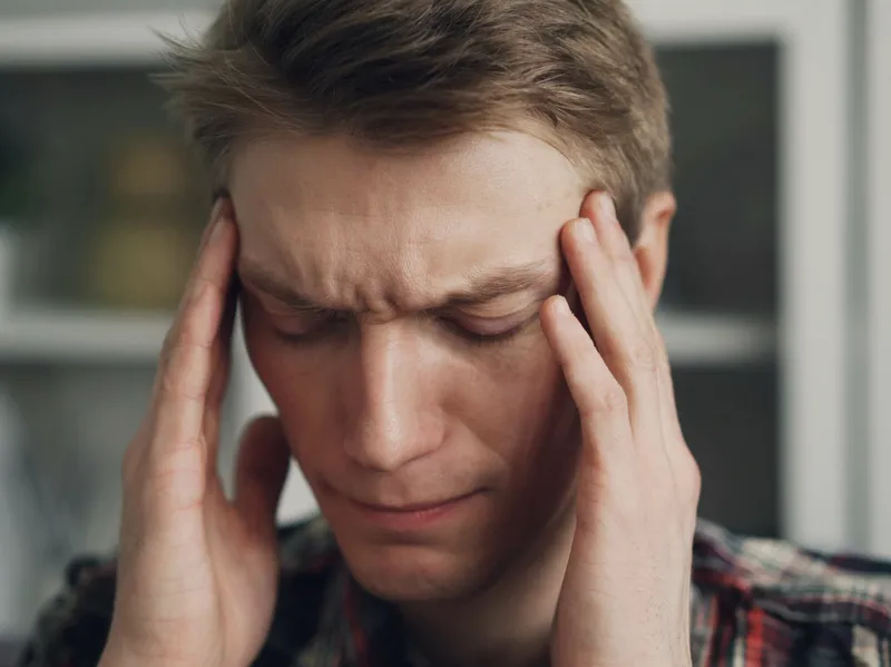 A man presses his fingers to his temples with a headache.