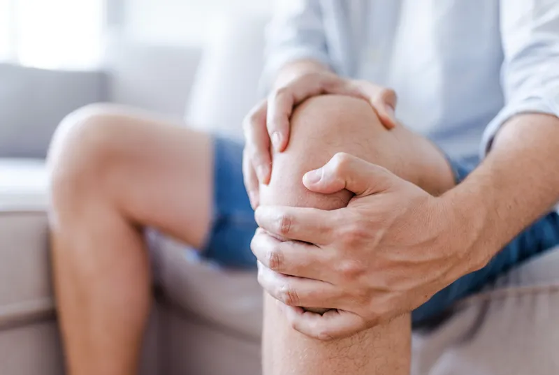A man holds his painful knee with both hands.